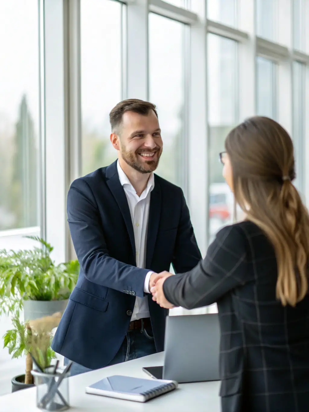 A professional IT consultant in a modern office setting, smiling and shaking hands with a client, symbolizing trust and partnership in IT consulting services.